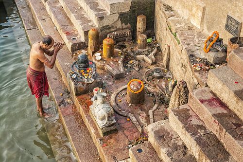 man offert eten aan de Ganges als onderdeel van een ochtendgebedritueel aan de Ganges rivier Ghat in