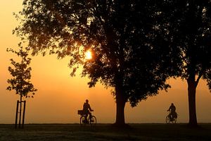 Cyclistes et arbres en silhouette le matin au lever du soleil sur Margriet Pflug