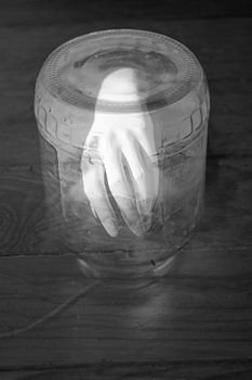 Surreal hand in black and white under a glass jar, double shot