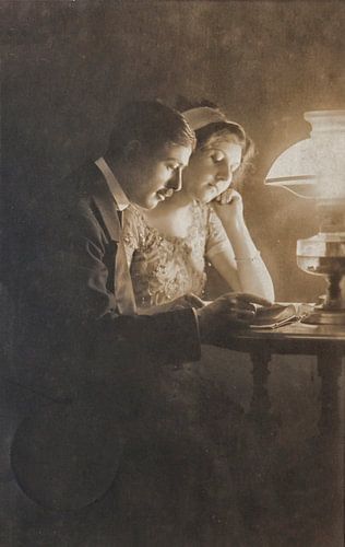 Un couple d'amoureux, en 1913, lit à la lueur d'une lampe à pétrole.