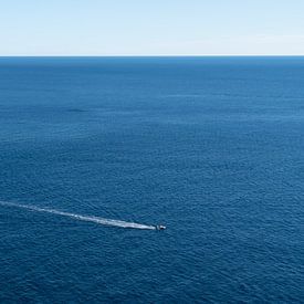 Un bateau glisse sur la mer bleue et calme sur Adriana Mueller