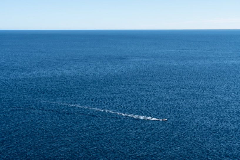 Un bateau glisse sur la mer bleue et calme par Adriana Mueller