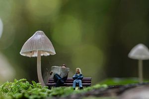 Miniaturfiguren entspannen auf einer Bank unter riesigen Pilzen