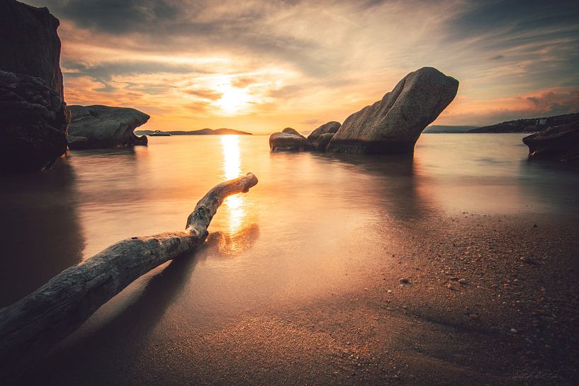 Zonsondergang aan de kust van Griekenland met strand en stenen en tak van Fotos by Jan Wehnert