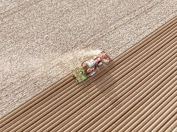 Tractor maakt de grond klaar voor het poten van pootaardappelen tijdens de lente