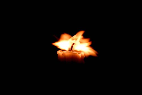Burning candle with moving flame against a black background