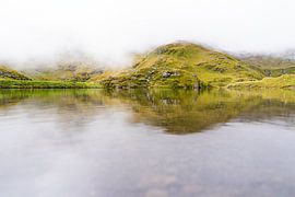 Lac de montagne brumeux dans un paysage de collines verdoyantes