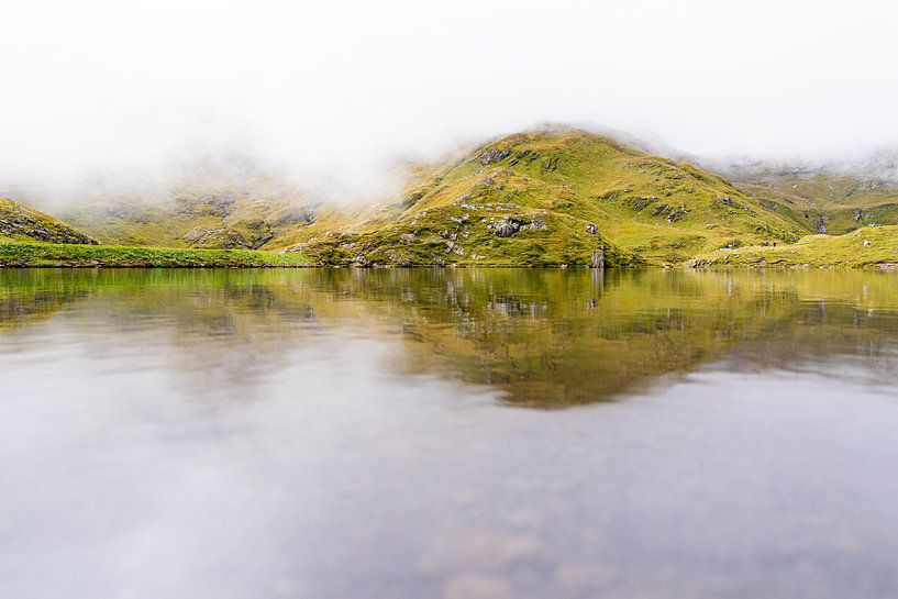 Misty mountain lake in green hilly landscape by Daisy Renders