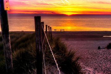 Oranje zonsondergang boven de zee op het strand van Rob Baken