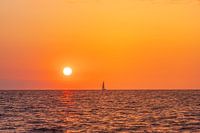 Sunset on the sea, on the horizon a sailing ship.