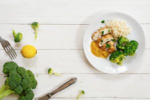 Gebakken kipfilet met een fruitige saus, broccoli en rijst en de ingrediënten op een wit geschilderd