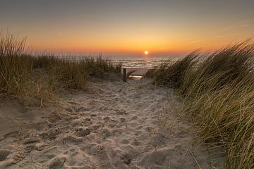 Uitzicht vanaf de duinen bij Petten op de ondergaande zon boven de Noordzee van Bram Lubbers