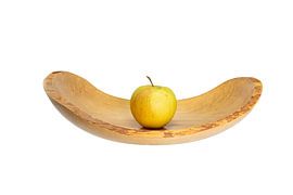 Side view of a flat wooden bowl with an apple in the middle exposed on white by Hans-Jürgen Janda