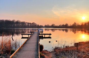 Kleiner Steg an einem See mit orange gelbem Sonnenuntergang