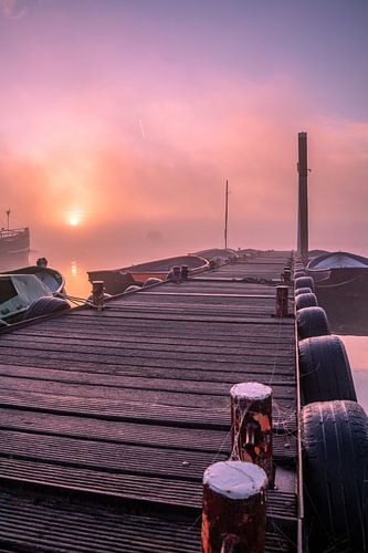 Un lever de soleil brumeux au bord de l'eau avec de belles couleurs dans le ciel.