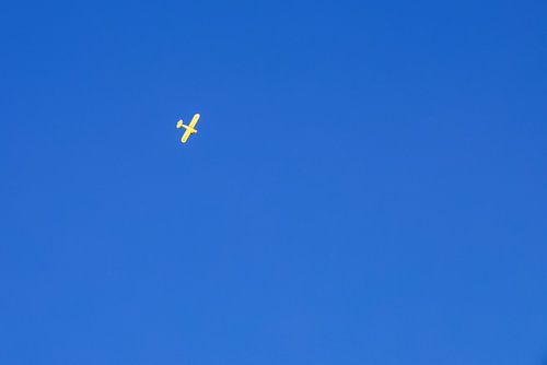 Avion jaune dans un ciel bleu et clair. sur Erik de Rijk