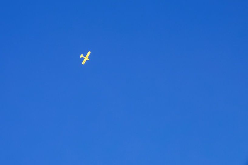 Geel vliegtuig in een heldere, blauwe lucht. van Erik de Rijk