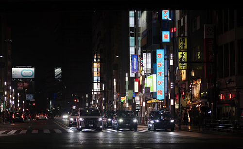 A street photograph taken in Tokyo at night, with neon signs in the background