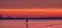 Een schaatser op het ijs van het Lauwersmeer tijdens zonsopkomst in de winter van Bas Meelker thumbnail