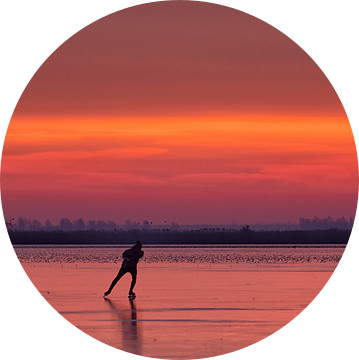 Een schaatser op het ijs van het Lauwersmeer tijdens zonsopkomst in de winter van Bas Meelker