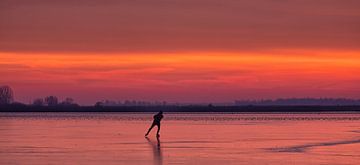 Een schaatser op het ijs van het Lauwersmeer tijdens zonsopkomst in de winter