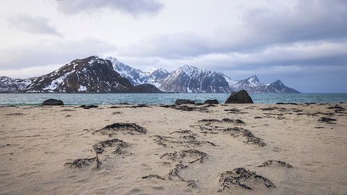 Golven kussen het zandstrand van Haukland onder de indrukwekkende L