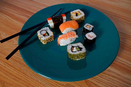 Sushi op een groen bord met eetstokjes