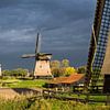 Three Dutch windmills against threatening sky by Inge van den Brande