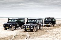 Drie zwarte Landrover Defenders op het strand van Terschelling