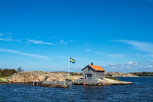Wooden cabin and flag on the island Valön in front of the town Fjällbacka in Sweden