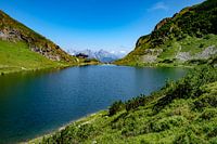 Rustikaler Bergsee mit Alpenlandschaft im Hintergrund