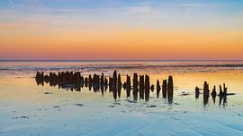 Houten paaltjes (golfbrekers) in de Waddenzee op Wieringen tijdens zonsondergang van Bram Lubbers