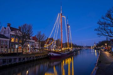 Versierde traditionele zeilboot in Harlingen Nederland in de kersttijd bij avond van Eye on You