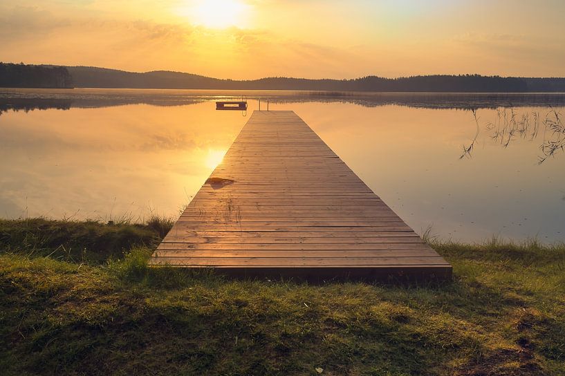 Footbridge, to the sunrise, reaching into a Swedish lake by Martin Köbsch