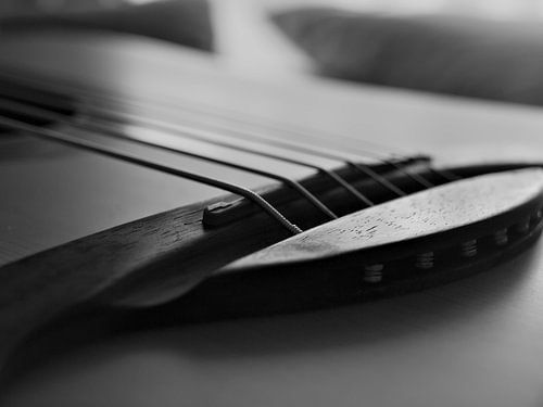 Een close up van de brug van een akoestische gitaar