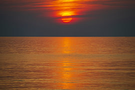 A blaze in the sky over a calm sea by Walter G. Allgöwer