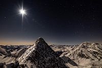 Bergtoppen in het maanlicht onder een sterrenhemel