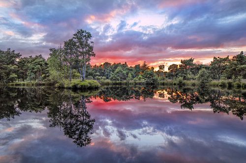 Tranquil lake at sunset with red colored clouds 