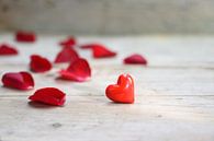 rood hart gemaakt van glas en rozenblaadjes op een rustieke grijze houten achtergrond, liefdesconcep van Maren Winter thumbnail
