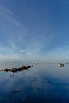 Photographie de voyage - mer calme avec des rochers et un bateau sur Ben De Kock