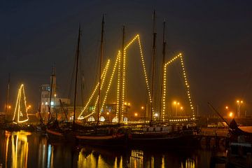 Geschmückte Segelboote zu Weihnachten im Hafen von Harlingen in den Niederlanden bei Sonnenuntergang von Eye on You