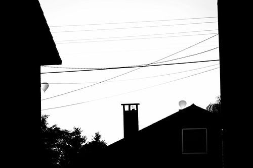Ballons monochromes au-dessus de toits en silhouette