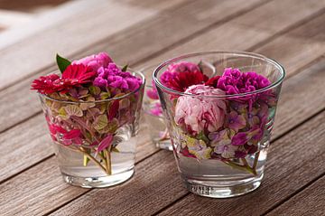 Prachtige verse gemengde bloemen gerangschikt in glazen vazen op houten tafel