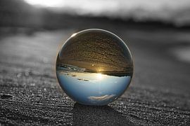 Blick durch die Glaskugel am Strand. Meer und Himmel im Hintergrund. von Martin Köbsch