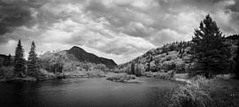 Storm clouds approaching a lake in an autumn forest