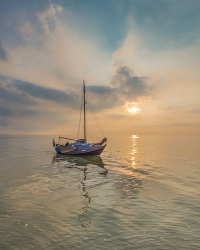 Scheepje vlak voor de haven van Laaxum, Friesland. bij zonsondergang. van Harrie Muis