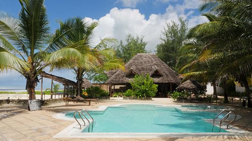 Swimmingpool mit Palmen und Bambushütte auf tropischer Insel