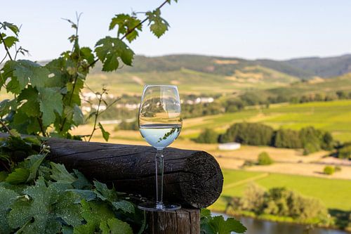 Filled wine glass next to wooden beams and Moselle landscape in the background