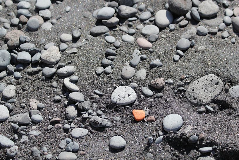Sei ein orangefarbener Stein an einem schwarzen Strand von Yoanique Essink
