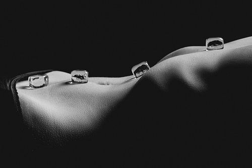 Ice cubes on bared female body in artistic light